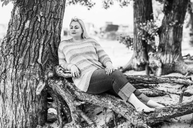 Artı plajda bir model. Şişman kadın hayattan zevk alıyor. Nehir kenarındaki doğada, kumların üzerinde dinlenen güzel bir kadın. Kadın hayatı kavramı.