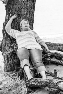 Artı plajda bir model. Şişman kadın hayattan zevk alıyor. Nehir kenarındaki doğada, kumların üzerinde dinlenen güzel bir kadın. Kadın hayatı kavramı.