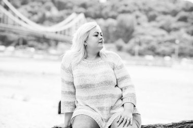 Artı plajda bir model. Şişman kadın hayattan zevk alıyor. Nehir kenarındaki doğada, kumların üzerinde dinlenen güzel bir kadın. Kadın hayatı kavramı.