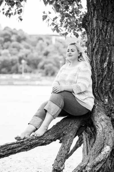 Artı plajda bir model. Şişman kadın hayattan zevk alıyor. Nehir kenarındaki doğada, kumların üzerinde dinlenen güzel bir kadın. Kadın hayatı kavramı.