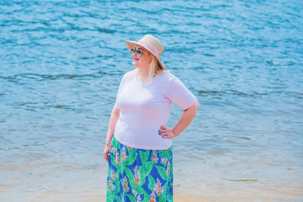 Artı plajda bir model. Şişman kadın hayattan zevk alıyor. Nehir kenarındaki doğada, kumların üzerinde dinlenen güzel bir kadın. Kadın hayatı kavramı.