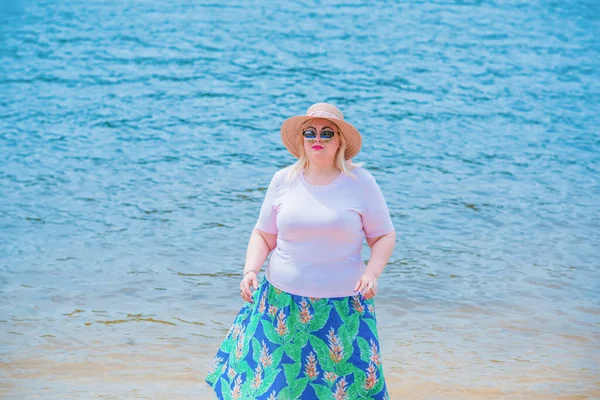 Artı plajda bir model. Şişman kadın hayattan zevk alıyor. Nehir kenarındaki doğada, kumların üzerinde dinlenen güzel bir kadın. Kadın hayatı kavramı.