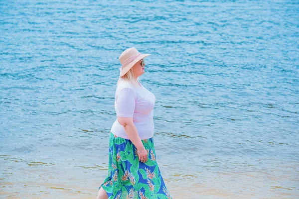 Artı plajda bir model. Şişman kadın hayattan zevk alıyor. Nehir kenarındaki doğada, kumların üzerinde dinlenen güzel bir kadın. Kadın hayatı kavramı.