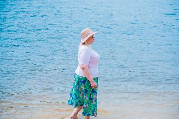 Artı plajda bir model. Şişman kadın hayattan zevk alıyor. Nehir kenarındaki doğada, kumların üzerinde dinlenen güzel bir kadın. Kadın hayatı kavramı.