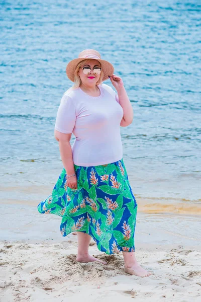 Artı plajda bir model. Şişman kadın hayattan zevk alıyor. Nehir kenarındaki doğada, kumların üzerinde dinlenen güzel bir kadın. Kadın hayatı kavramı.