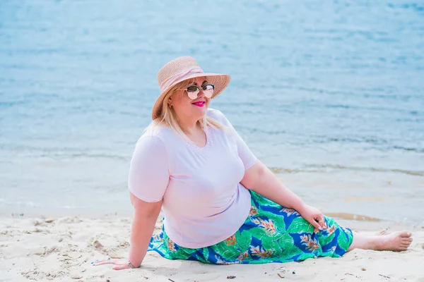 Artı plajda bir model. Şişman kadın hayattan zevk alıyor. Nehir kenarındaki doğada, kumların üzerinde dinlenen güzel bir kadın. Kadın hayatı kavramı.