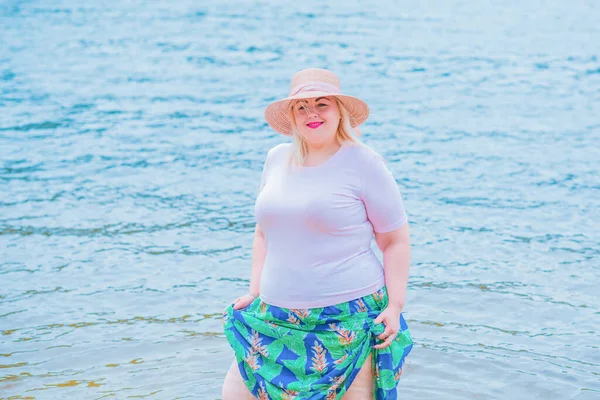 Artı plajda bir model. Şişman kadın hayattan zevk alıyor. Nehir kenarındaki doğada, kumların üzerinde dinlenen güzel bir kadın. Kadın hayatı kavramı.