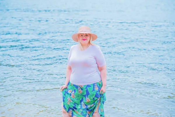 Artı plajda bir model. Şişman kadın hayattan zevk alıyor. Nehir kenarındaki doğada, kumların üzerinde dinlenen güzel bir kadın. Kadın hayatı kavramı.