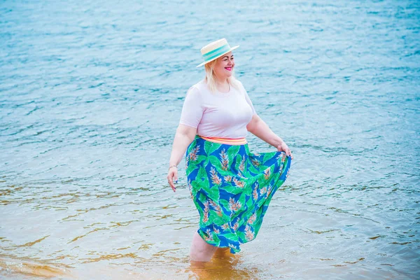 Artı plajda bir model. Şişman kadın hayattan zevk alıyor. Nehir kenarındaki doğada, kumların üzerinde dinlenen güzel bir kadın. Kadın hayatı kavramı.