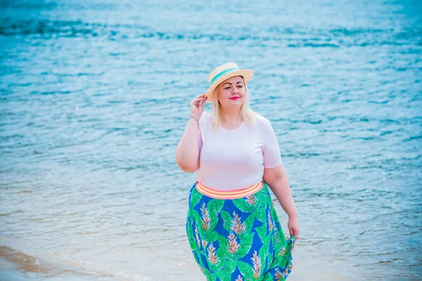 Artı plajda bir model. Şişman kadın hayattan zevk alıyor. Nehir kenarındaki doğada, kumların üzerinde dinlenen güzel bir kadın. Kadın hayatı kavramı.