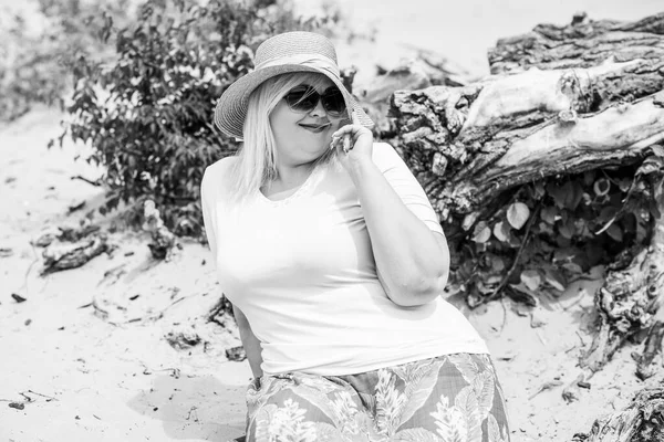 Artı plajda bir model. Şişman kadın hayattan zevk alıyor. Nehir kenarındaki doğada, kumların üzerinde dinlenen güzel bir kadın. Kadın hayatı kavramı.