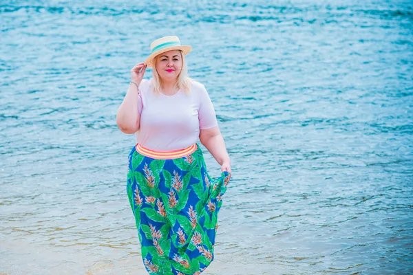 Artı plajda bir model. Şişman kadın hayattan zevk alıyor. Nehir kenarındaki doğada, kumların üzerinde dinlenen güzel bir kadın. Kadın hayatı kavramı.