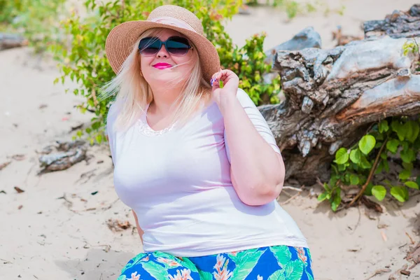 Artı plajda bir model. Şişman kadın hayattan zevk alıyor. Nehir kenarındaki doğada, kumların üzerinde dinlenen güzel bir kadın. Kadın hayatı kavramı.