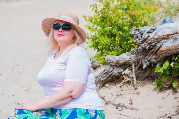 Artı plajda bir model. Şişman kadın hayattan zevk alıyor. Nehir kenarındaki doğada, kumların üzerinde dinlenen güzel bir kadın. Kadın hayatı kavramı.