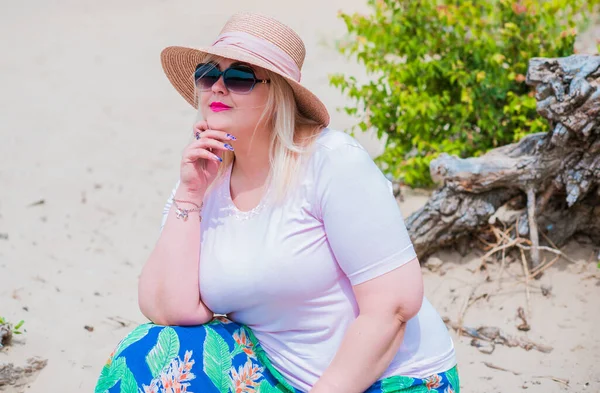 Artı plajda bir model. Şişman kadın hayattan zevk alıyor. Nehir kenarındaki doğada, kumların üzerinde dinlenen güzel bir kadın. Kadın hayatı kavramı.