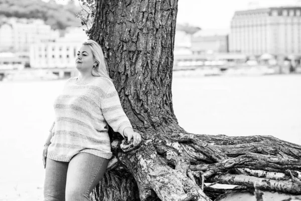 Artı plajda bir model. Şişman kadın hayattan zevk alıyor. Nehir kenarındaki doğada, kumların üzerinde dinlenen güzel bir kadın. Kadın hayatı kavramı.