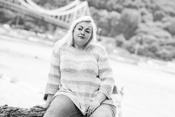 Artı plajda bir model. Şişman kadın hayattan zevk alıyor. Nehir kenarındaki doğada, kumların üzerinde dinlenen güzel bir kadın. Kadın hayatı kavramı.