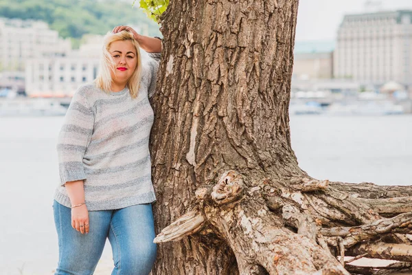 Artı plajda bir model. Şişman kadın hayattan zevk alıyor. Nehir kenarındaki doğada, kumların üzerinde dinlenen güzel bir kadın. Kadın hayatı kavramı.