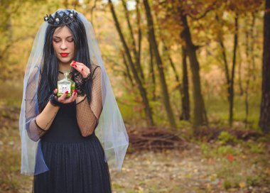 Karanlık bir ormanda cadılar bayramı cadısı. Modern cadılar gibi giyinmiş güzel bir kadın. Cadılar Bayramı sanat tasarımı. Cadılar Bayramı Konsepti için karanlık tema