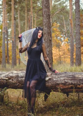 Karanlık bir ormanda cadılar bayramı cadısı. Modern cadılar gibi giyinmiş güzel bir kadın. Cadılar Bayramı sanat tasarımı. Cadılar Bayramı Konsepti için karanlık tema