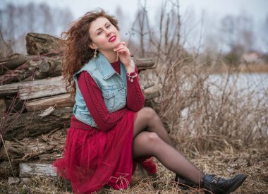 Kot yelek ve Marsala elbisesi içinde şık bir kadın.