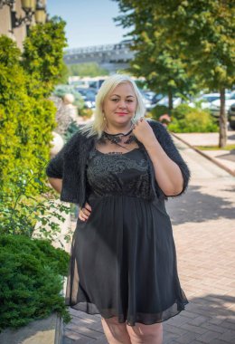 Artı cüsseli bir kadın, Amerikan ya da Avrupalı görünümlü bir kadın şehirde hayatın tadını çıkarıyor. Aşırı kilolu genç bir bayan, şehrin merkezinde şık bir şekilde giyinmiş. Doğal güzellik.