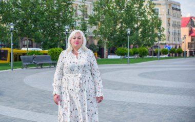 Artı cüsseli bir kadın, Amerikan ya da Avrupalı görünümlü bir kadın şehirde hayatın tadını çıkarıyor. Aşırı kilolu genç bir bayan, şehrin merkezinde şık bir şekilde giyinmiş. Doğal güzellik.