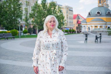 Artı cüsseli bir kadın, Amerikan ya da Avrupalı görünümlü bir kadın şehirde hayatın tadını çıkarıyor. Aşırı kilolu genç bir bayan, şehrin merkezinde şık bir şekilde giyinmiş. Doğal güzellik.