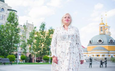 Artı cüsseli bir kadın, Amerikan ya da Avrupalı görünümlü bir kadın şehirde hayatın tadını çıkarıyor. Aşırı kilolu genç bir bayan, şehrin merkezinde şık bir şekilde giyinmiş. Doğal güzellik.