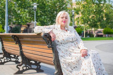 Artı cüsseli bir kadın, Amerikan ya da Avrupalı görünümlü bir kadın şehirde hayatın tadını çıkarıyor. Aşırı kilolu genç bir bayan, şehrin merkezinde şık bir şekilde giyinmiş. Doğal güzellik.