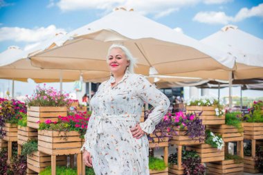 Artı cüsseli bir kadın, Amerikan ya da Avrupalı görünümlü bir kadın şehirde hayatın tadını çıkarıyor. Aşırı kilolu genç bir bayan, şehrin merkezinde şık bir şekilde giyinmiş. Doğal güzellik.