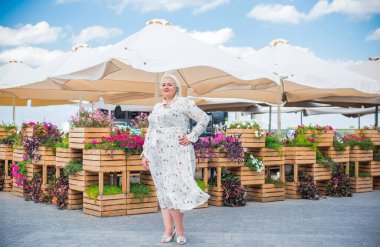 Artı cüsseli bir kadın, Amerikan ya da Avrupalı görünümlü bir kadın şehirde hayatın tadını çıkarıyor. Aşırı kilolu genç bir bayan, şehrin merkezinde şık bir şekilde giyinmiş. Doğal güzellik.