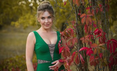 Yeşil elbiseli zarif bir kadın, kadın kıyafeti. Hanımlar için süslü bir tarz, sonbahar renkleri ve moda detayları. güzel renkler 