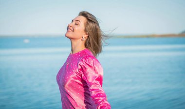 Pembe ipek benekli elbise içinde şık, mutlu bir kadın. Modern sarışın kadın romantik tarzda yetiştirildi. 