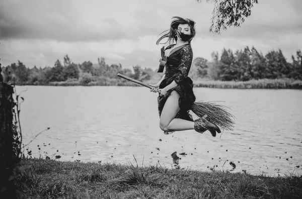 Genç, güzel ve gizemli cadı kadın ormanda Broom 'da uçuyor. Havalanma, şapkalı bir cadı süpürgede uçar, boş alan. Cadılar Bayramı tatili, sihir