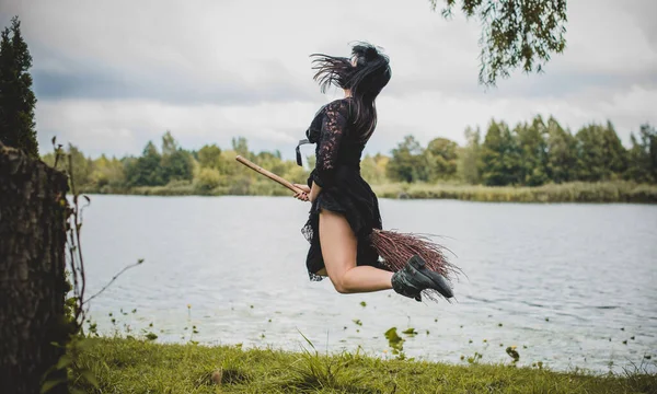 Genç, güzel ve gizemli cadı kadın ormanda Broom 'da uçuyor. Havalanma, şapkalı bir cadı süpürgede uçar, boş alan. Cadılar Bayramı tatili, sihir