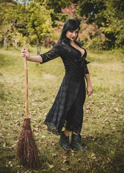 Cadılar bayramı için göz alıcı bir klasik görünümlü gotik kadın, süpürgeli bir cadı. Klasik kıyafetler içinde güzel bir vatandaş. El yapımı güzel aksesuarlar. Cadılar Bayramı için fikirler