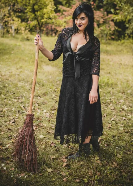 Cadılar bayramı için göz alıcı bir klasik görünümlü gotik kadın, süpürgeli bir cadı. Klasik kıyafetler içinde güzel bir vatandaş. El yapımı güzel aksesuarlar. Cadılar Bayramı için fikirler