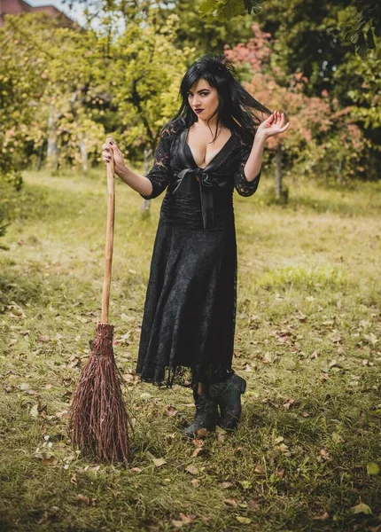 Cadılar bayramı için göz alıcı bir klasik görünümlü gotik kadın, süpürgeli bir cadı. Klasik kıyafetler içinde güzel bir vatandaş. El yapımı güzel aksesuarlar. Cadılar Bayramı için fikirler