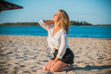 Dinlenme zamanı, zarif kadın plajda dinleniyor. Güzel kadınsı sarı saçlı bayan, sükunet ve özgürlük kavramı.