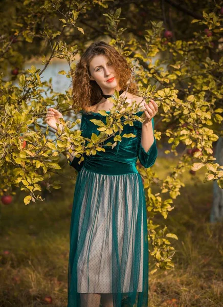 Woman in green velvet romantic dress, ladies pretty style, autumn nature at background