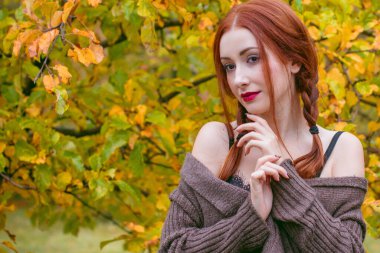 Modaya uygun bir kadın gündelik kıyafetler giyer, güzel bir yüz, kızıl doğal saçlar, sonbahar koleksiyonu, açık havada moda giysileri.