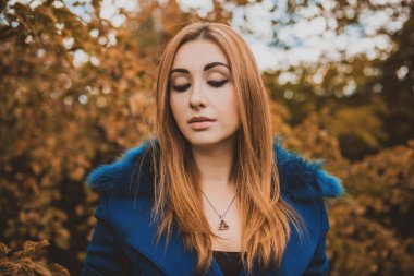 Sonbahar kadınları moda, şık makyaj ve saç stili. Klasik tonlarda kadın portresi. Mavi kürklü kızıl saçlı kadın.