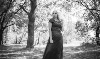 Vintage şıklığı. Klasik tonlarda portre ve dantelli etekli kadın ormanda dikiliyor ve doğa ile eğleniyor. Kendini sevme ve uyum kavramı.