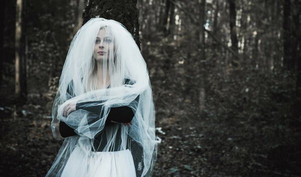 Mystical scene at forest, girl at bride costume, with a veil, Halloween ideas