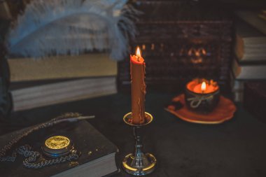 Eskimiş bir masada turuncu mum, karanlık akademi estetiği. Akşam Ekim zamanı