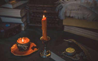 Eskimiş bir masada turuncu mum, karanlık akademi estetiği. Akşam Ekim zamanı