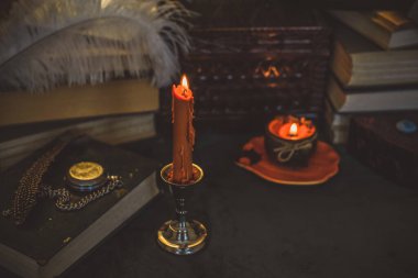 Eskimiş bir masada turuncu mum, karanlık akademi estetiği. Akşam Ekim zamanı