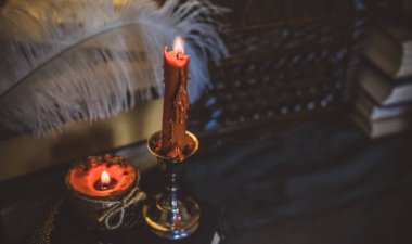 Eskimiş bir masada turuncu mum, karanlık akademi estetiği. Akşam Ekim zamanı