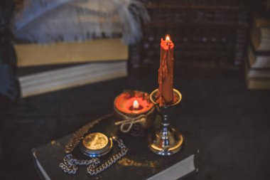 Eskimiş bir masada turuncu mum, karanlık akademi estetiği. Akşam Ekim zamanı